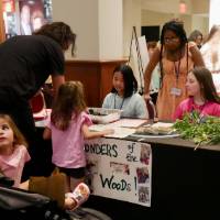Young kid and guest learn from students about the "Wonders of the Woods"